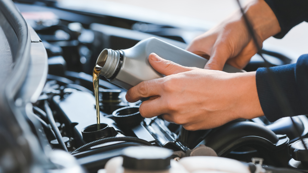 Image of a person pouring oil into a vehicle.
